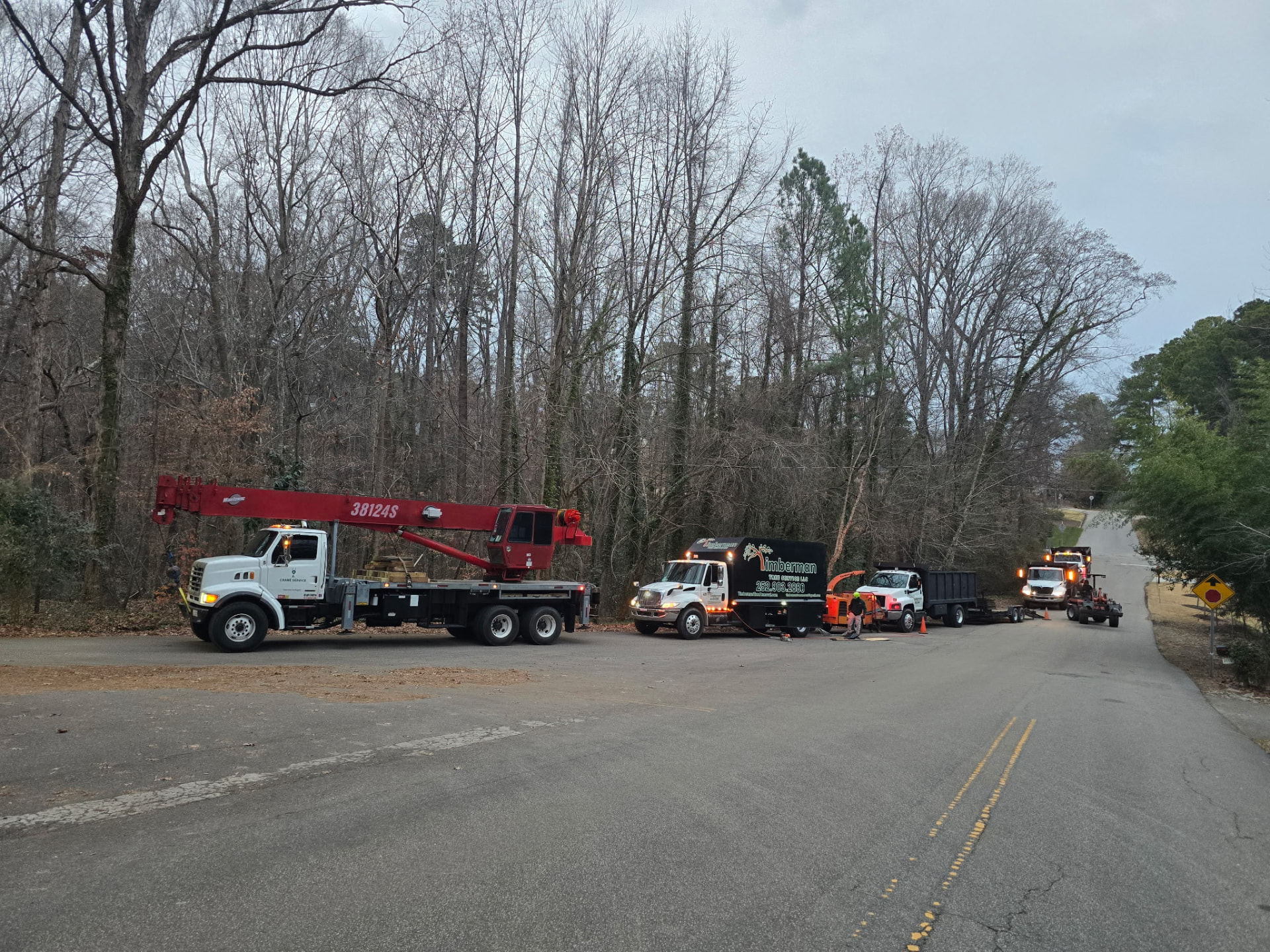 Crane tree removal setup with chipper and Timberman trucks on a residential street in Wake County, NC
